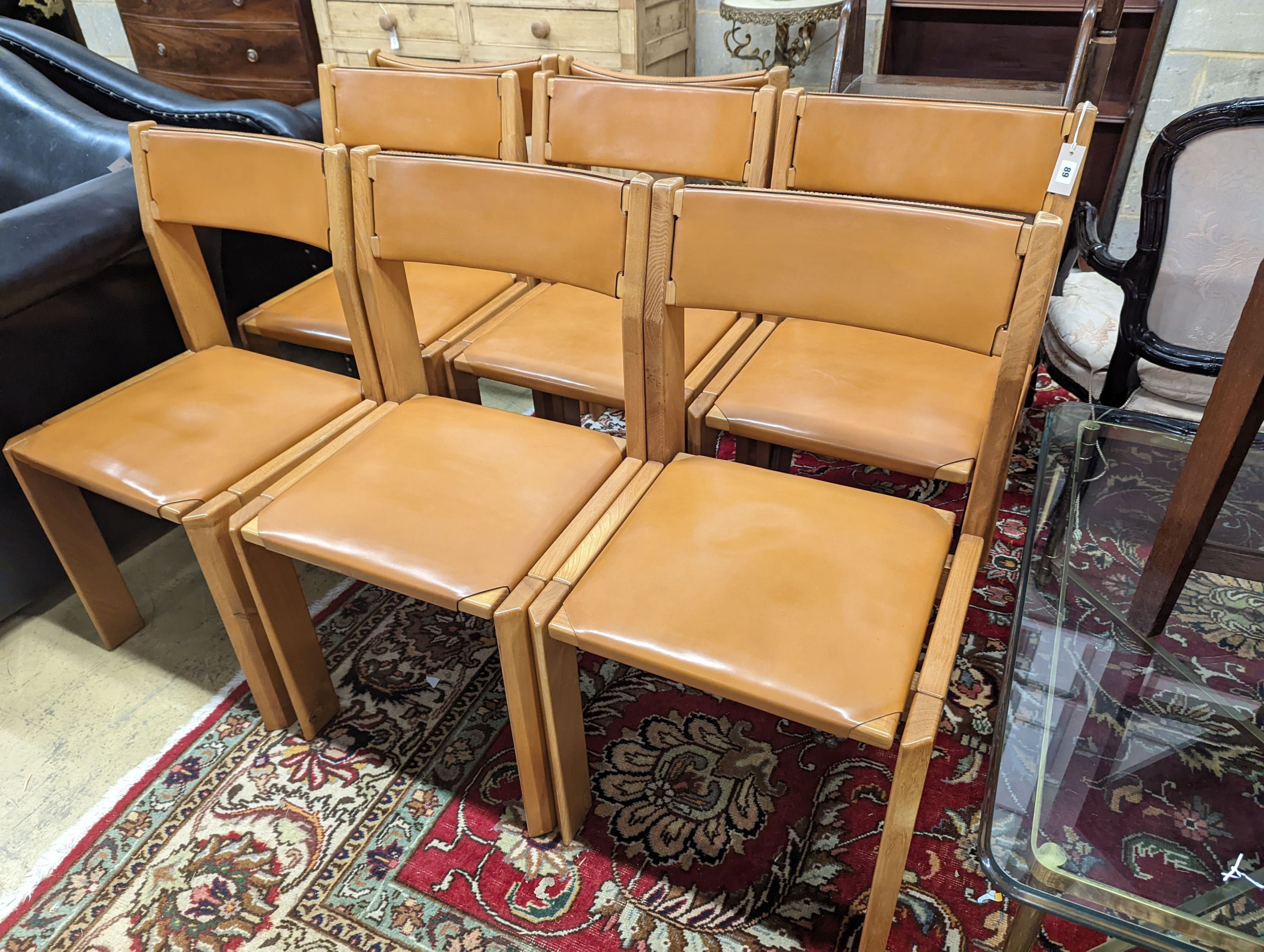 A set of eight mid century design walnut and tan leather dining chairs, width 48cm, depth 44cm, height 84cm